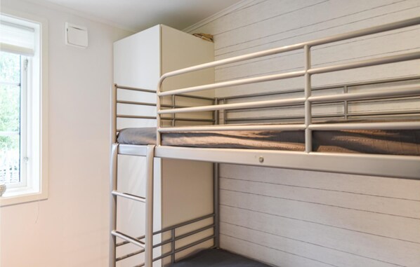 A bunk bed with a wardrobe above it, a window on the left, and a white wall with horizontal lines.