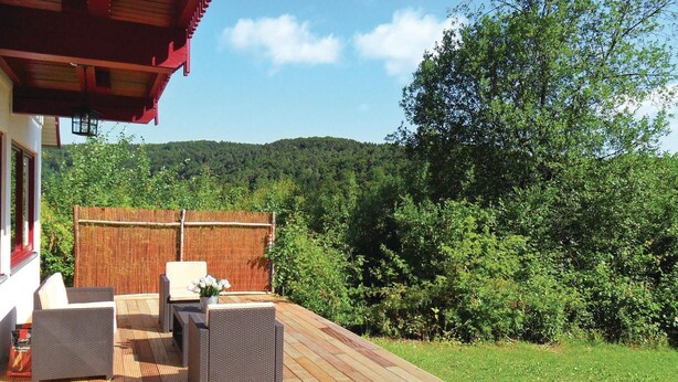 A wooden deck with outdoor furniture, a bamboo fence, and a view of a forested hillside. - Awesome Home in Kirchheim With 3 Bedrooms (Kirchheim)