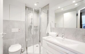 Une salle de bain moderne avec une douche à parois de verre, un lavabo blanc et des toilettes.