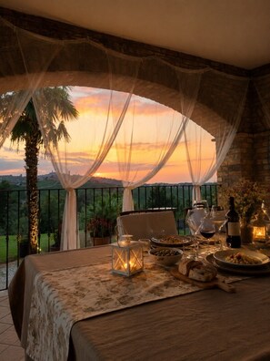 A balcony with a table set for dining, a bottle of wine, and a lantern. - The Country House, totally exclusive for groups and family units. (Piemonte)