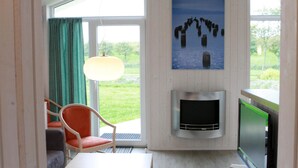 Een kamer met een televisie, een schilderij, een stoel en een raam met gordijnen.