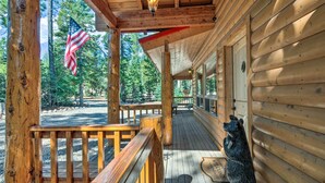 A wooden cabin with a porch, a bear statue, and an American flag. - Duck Creek Village Cabin: Hike, Ski, & Bike! (Duck Creek Village)