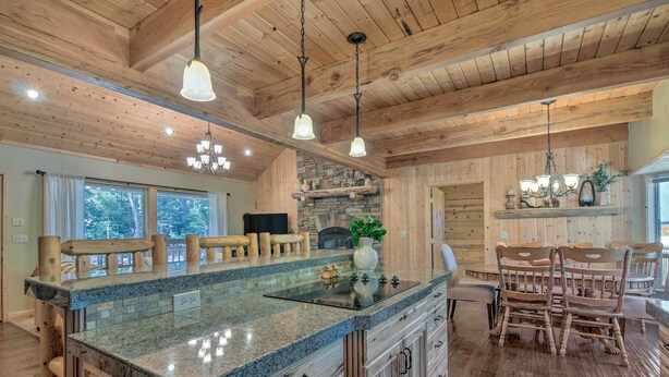 A spacious kitchen with a granite countertop, wooden cabinets, and a stone accent wall. - Duck Creek Village Cabin: Hike, Ski, & Bike! (Duck Creek Village)