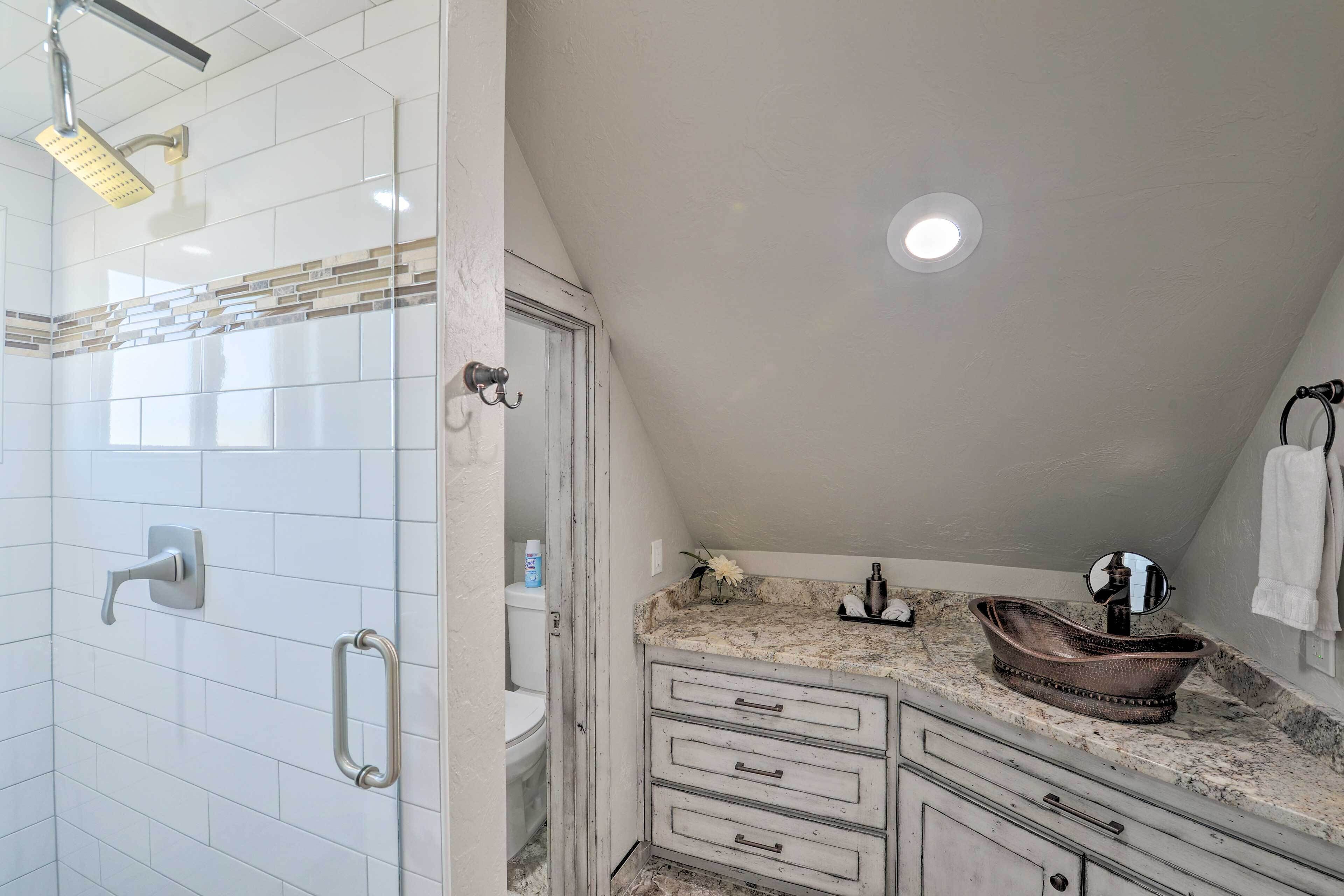 A bathroom with a shower, toilet, vanity, and a sink with a mirror.