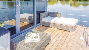 Una terraza con mobiliario de mimbre y una mesa con una bandeja de objetos.