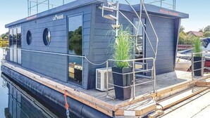 Una moderna casa flotante con una placa que dice 'LA MARE' y una escalera que lleva a una cubierta superior.