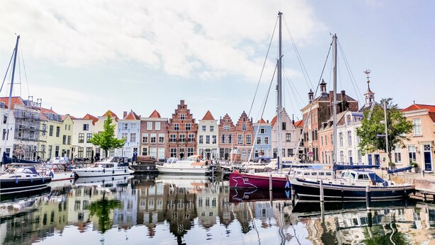 A canal with boats docked, surrounded by historic buildings with red-tiled roofs. - Amazing Home in Heinkenszand With 2 Bedrooms, Wifi and Outdoor Swimming Pool (Heinkenszand)