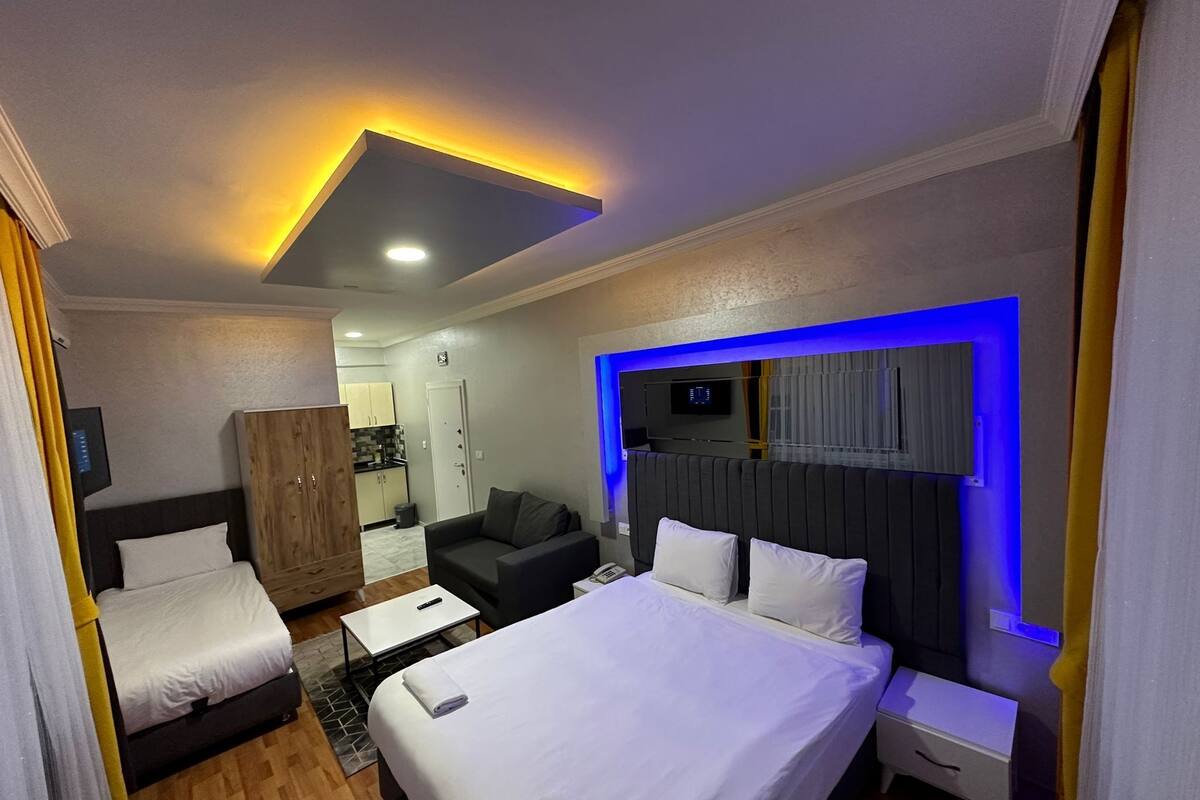 A hotel room with a bed, a sofa, a desk, and a TV mounted on the wall.