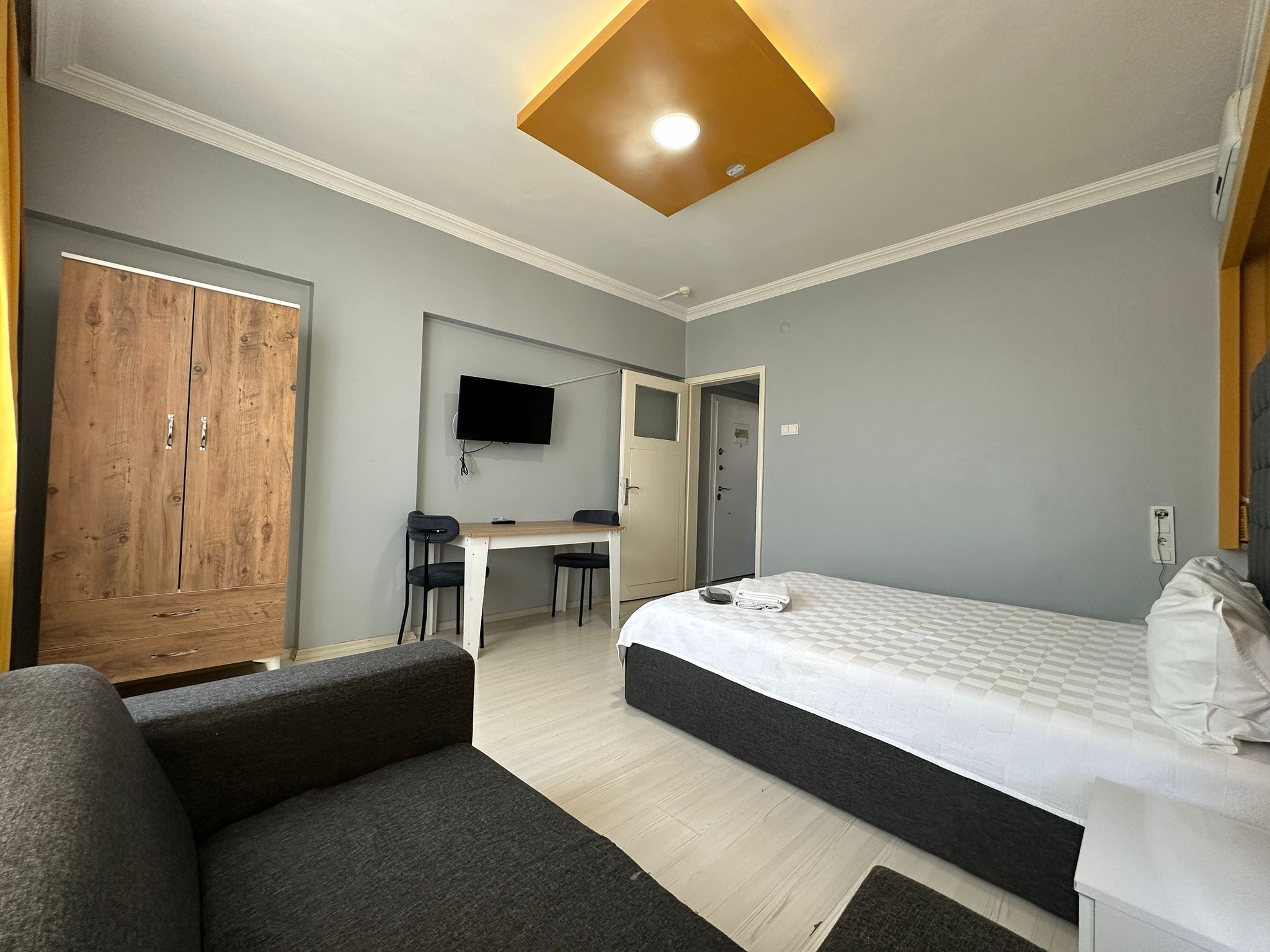 A modern bedroom with a bed, a desk, a chair, and a wardrobe.