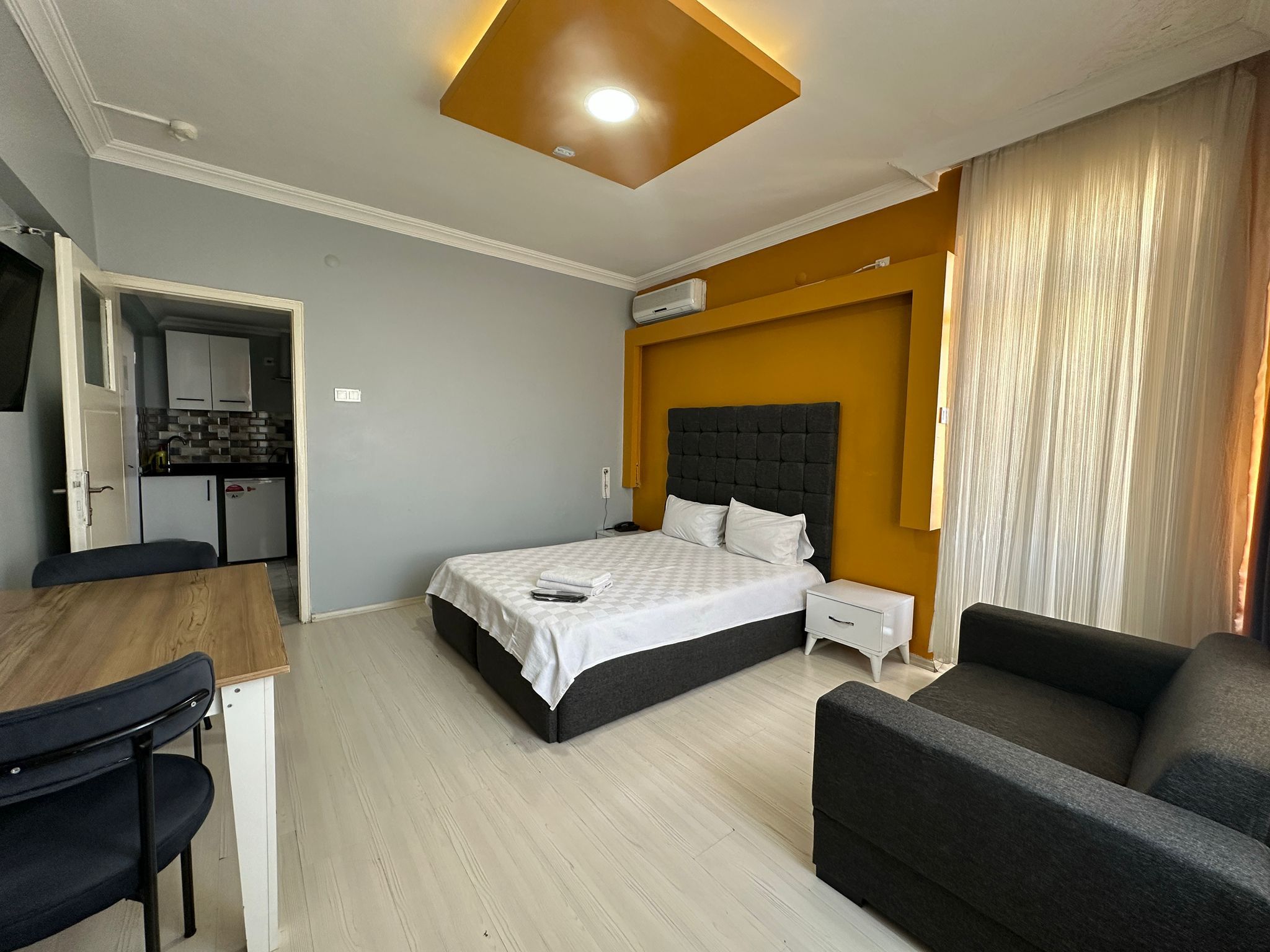 Une chambre d’hôtel comprenant un lit, un bureau, une chaise, un canapé, un coin cuisine et une salle de bain.