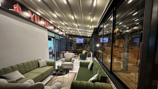 A modern lounge area with green sofas, a small coffee table, and a TV screen. - YILDIRIM SUİT APART OTEL (Ankara)