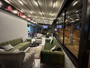 A modern lounge area with green sofas, a small coffee table, and a TV screen.