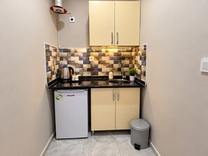 A compact kitchen with a refrigerator, sink, and cabinets. - YILDIRIM SUİT APART OTEL (Ankara)