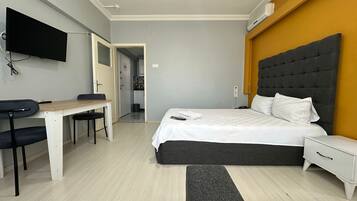 Een moderne slaapkamer met een bed, nachtkastje en bureau met stoel.