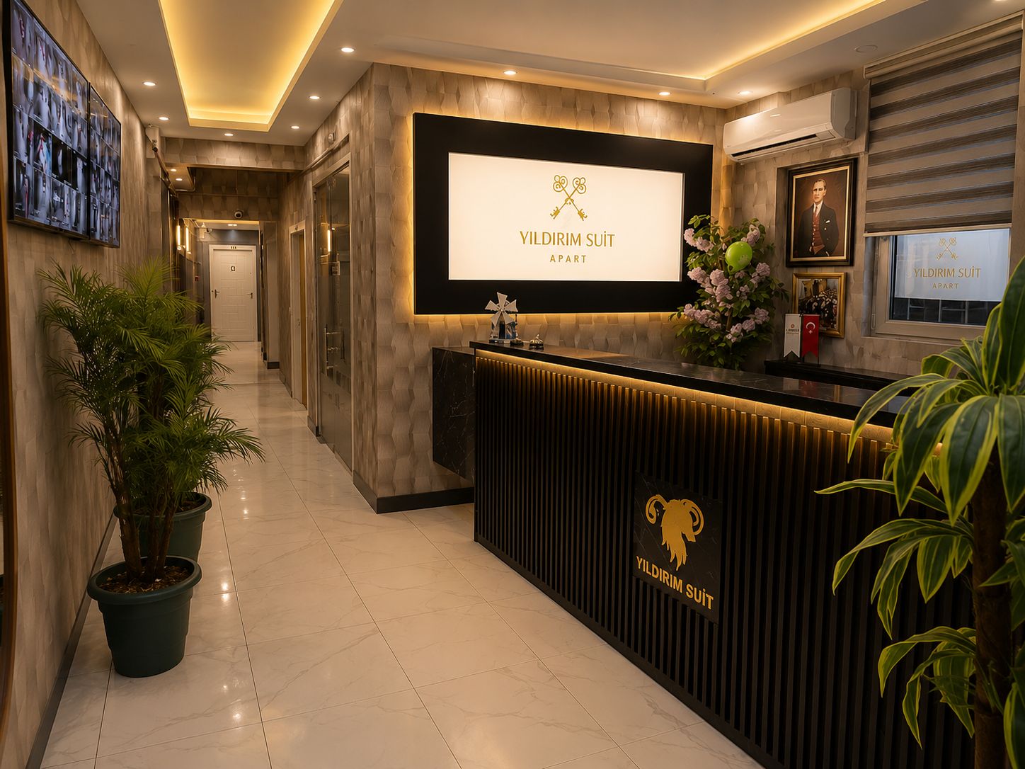 A hotel reception area with a reception desk, a large framed sign, and a potted plant.
