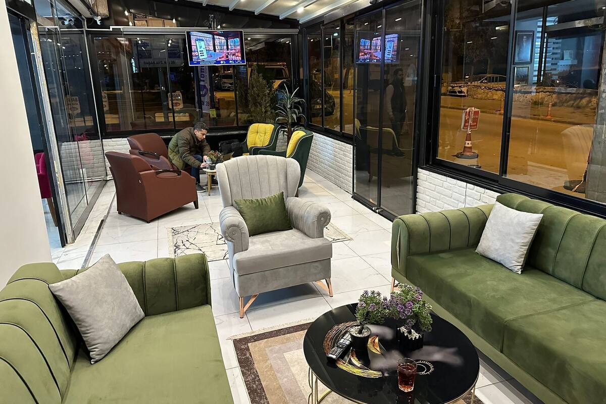 A modern interior with green sofas, a grey armchair, and a black coffee table with decorative items.