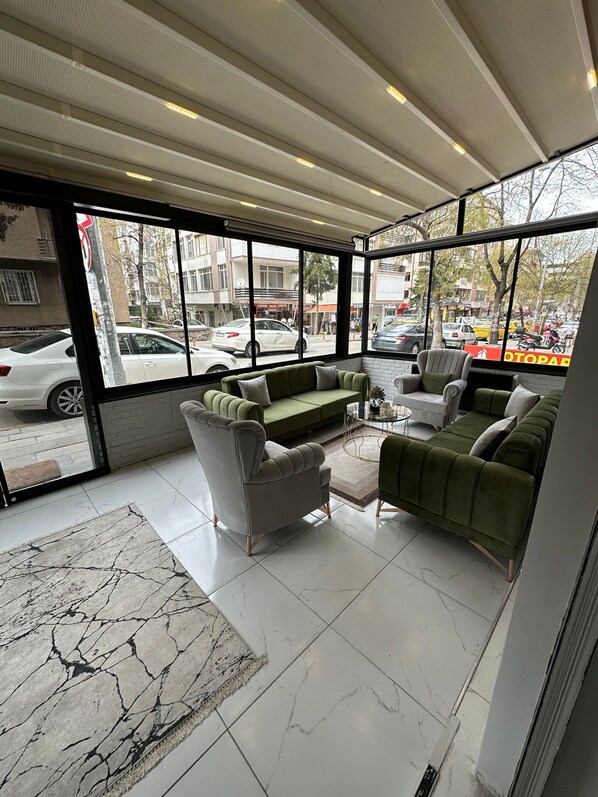 Un interior moderno con un sofá verde, un sillón gris y una alfombra estampada.