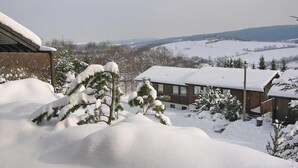Un paisaje nevado con un edificio de techo plano y una ventana visible.