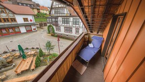 A balcony with a view of a courtyard, wooden benches, and a small garden area. - Nice Apartment in Schonach With 2 Bedrooms and Wifi (Schonach im Schwarzwald)