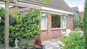 Una casa de ladrillo con techo de tejas, una pérgola de madera y una antena parabólica.