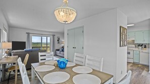 A dining area with a wooden table, white chairs, and a chandelier.