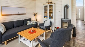A cozy living room with a sofa, a coffee table, a chair, a cabinet with glass doors, and a wood-burning stove. - Amazing Home in Krems Ii/warderbrück With 2 Bedrooms, Sauna and Wifi (Krems II)