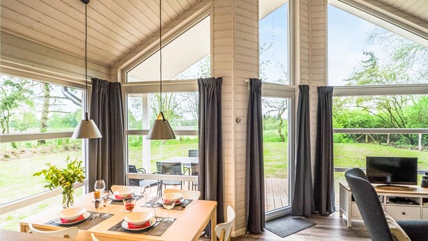 A dining area with a wooden table set for four, two pendant lights, and a view of a garden through large windows. - Amazing Home in Krems Ii/warderbrück With 2 Bedrooms, Sauna and Wifi (Krems II)