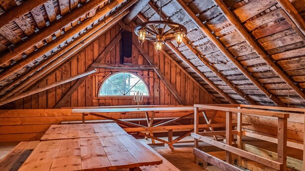 An attic room with a wooden bench, a table, and a chandelier.