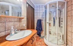 Een badkamer met een wit wastafel, een spiegel, een douchecabine en een handdoekrek.
