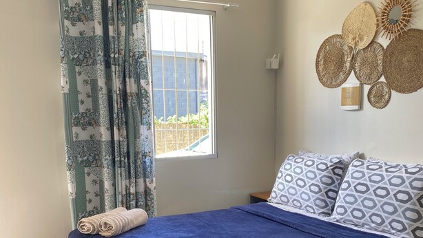 A bedroom with a bed, curtains, a window, and wall decorations. - Apartamento encantador (Florianópolis)