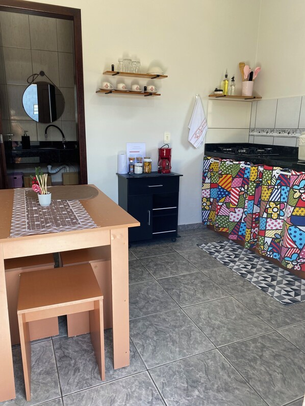 A kitchen with a wooden table, a black cabinet, and a colorful backsplash. - Apartamento encantador (Florianópolis)