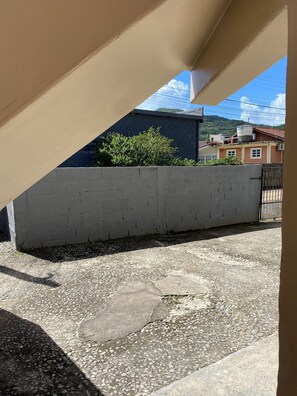 A concrete wall, a gravel ground, and a building with a red roof in the background. - Apartamento encantador (Florianópolis)