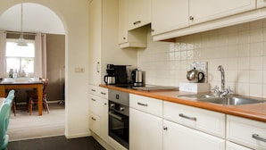 A kitchen with white cabinets, a wooden countertop, a sink, and a dining area with a table and chairs.