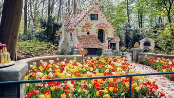 Un jardín caprichoso con una casa colorida rodeada de diversas tulipanes.