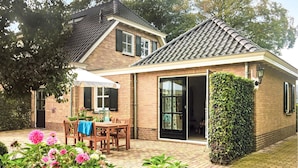 A two-story house with a tiled roof, a brick exterior, and a large sliding glass door.