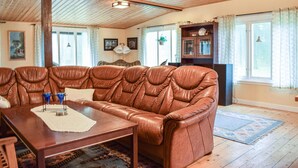 Een woonkamer met een bruine leren bank, een houten tafel en een donker houten kast.
