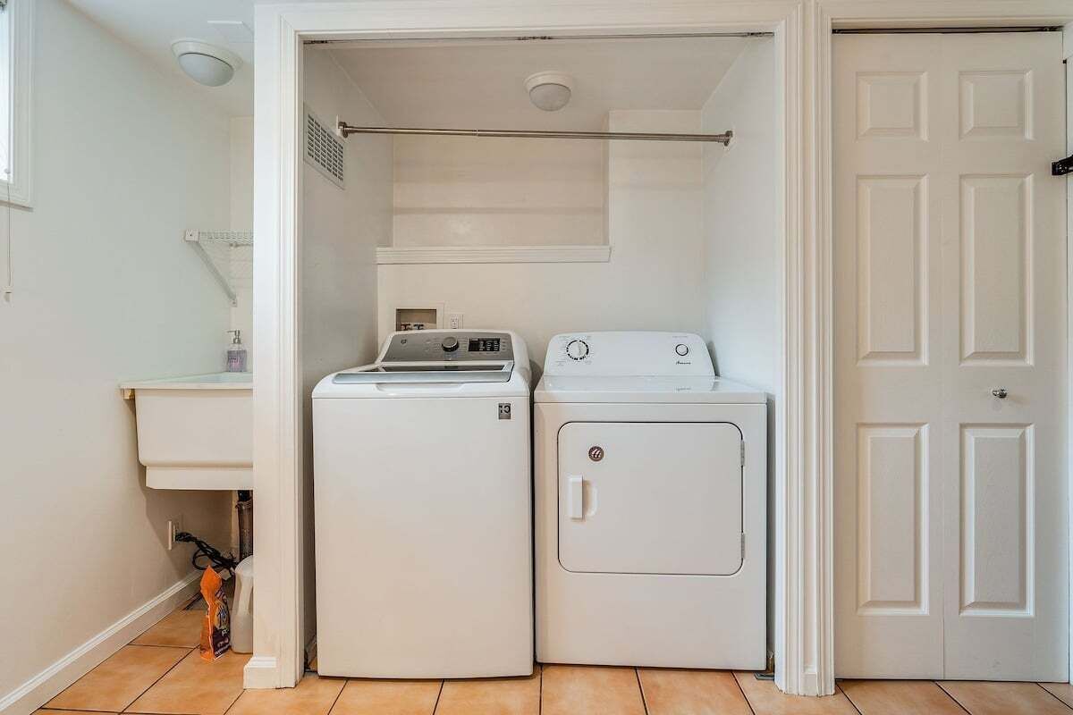Une buanderie équipée d’un lave-linge et d’un sèche-linge, avec une porte blanche et une petite fenêtre.