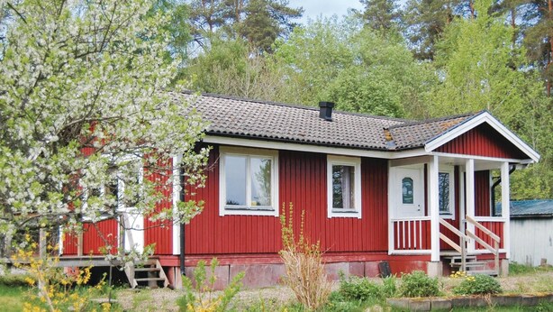 Une maison en bois rouge avec un toit en tuiles, une véranda et un petit jardin.