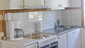 Une cuisine de taille réduite, avec des meubles blancs, une cuisinière et une machine à café.