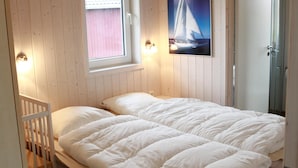 A bedroom with a bed, a window, and a wall-mounted picture of a sailboat. - Friedrichskoog/deichblick 7 (Friedrichskoog)