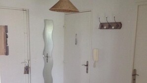 Ein Zimmer mit Fliesenboden, einer weißen Tür mit Spiegel, einem Deckenventilator und einem Wandheizgerät.