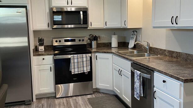A modern kitchen with white cabinets, stainless steel appliances, and a granite countertop. - Quiet and cozy, a remodeled dairy with panoramic mountain views. . (Salem)