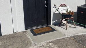 A black door with a small window, a welcome sign, and a potted plant on a wooden stool. - Quiet and cozy, a remodeled dairy with panoramic mountain views. . (Salem)