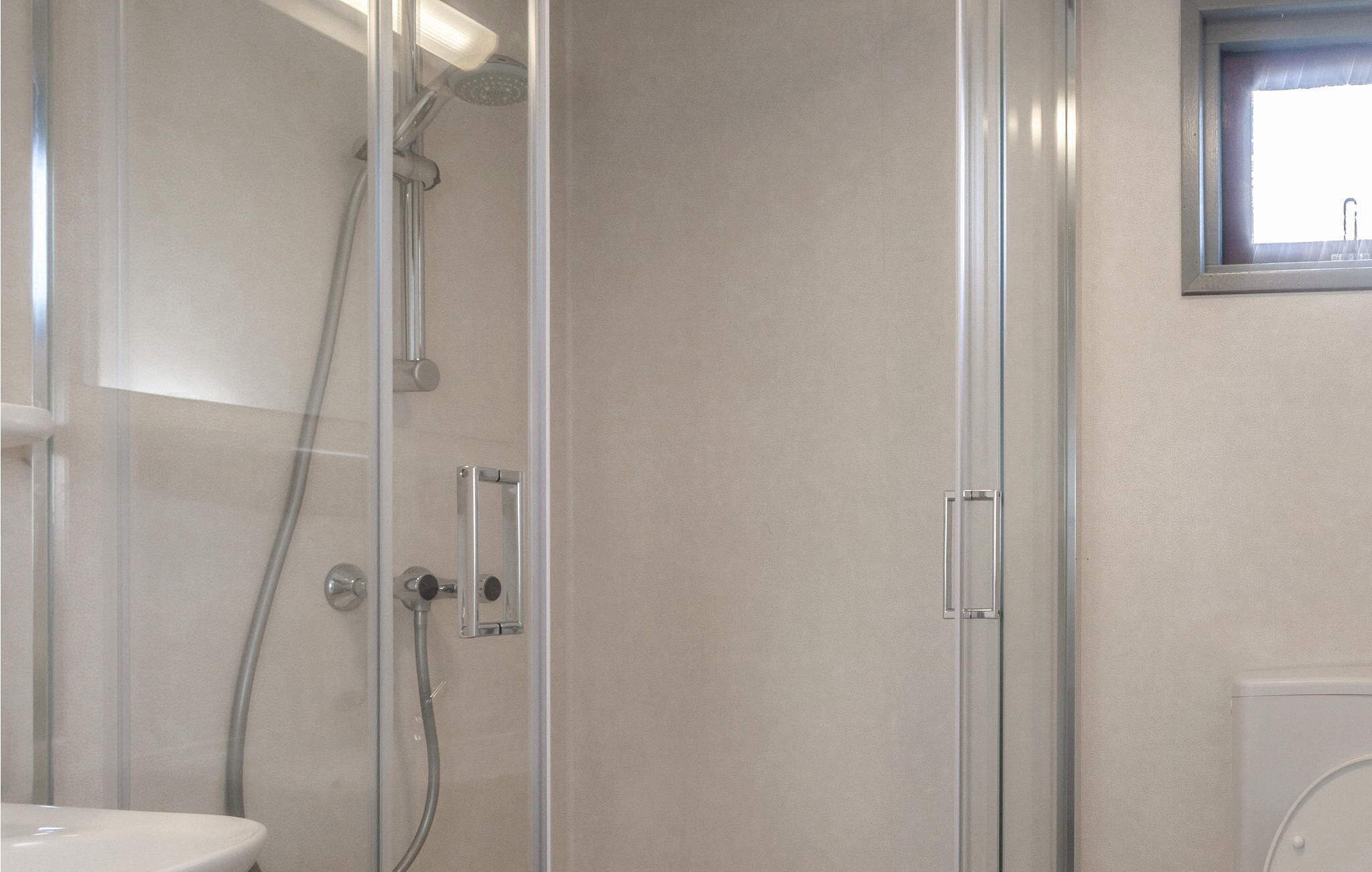 Ein modernes Badezimmer mit Duschkabine aus Glas, Toilette und Waschbecken.