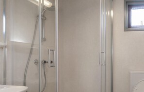 Ein modernes Badezimmer mit Duschkabine aus Glas, Toilette und Waschbecken.