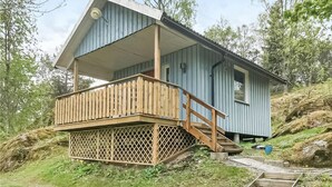 Une petite cabane à un seul étage, dotée d’une terrasse en bois et d’un porche abrité.