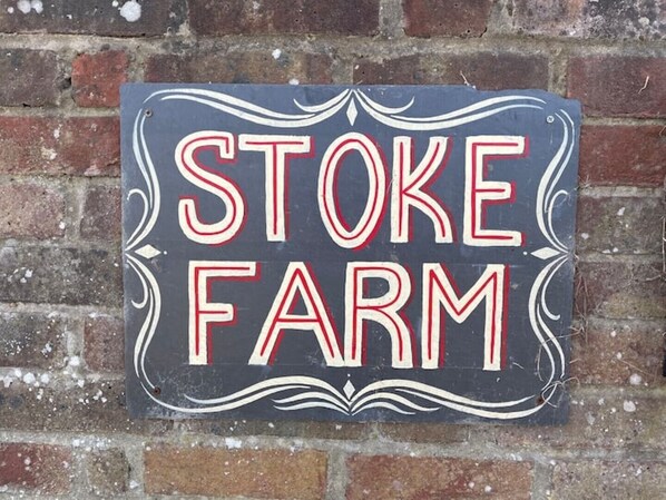 Un letrero con el texto 'STOKE FARM' en una pared de ladrillo.