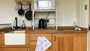 Une cuisine avec des meubles de rangement en bois, un four à micro-ondes, une bouilloire et un évier.