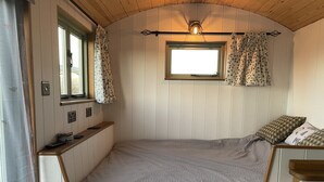 Une chambre à coucher de taille réduite, avec un lit, une petite fenêtre et une table de chevet.