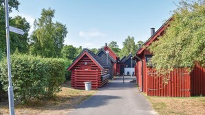A narrow pathway leading to a row of red wooden buildings with a sign indicating '1a Tværgatan'. - Klitterbyn 16 (Angelholm)
